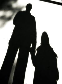 Low angle view of silhouette people standing against white wall