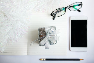 Close-up of christmas decoration with book and eyeglasses on white background