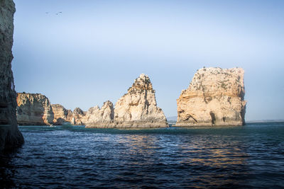 Rock formations in sea against clear sky