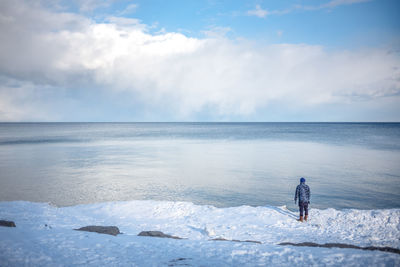 Man on lake against sky during winter