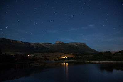 Scenic view of lake and mountains against sky at night