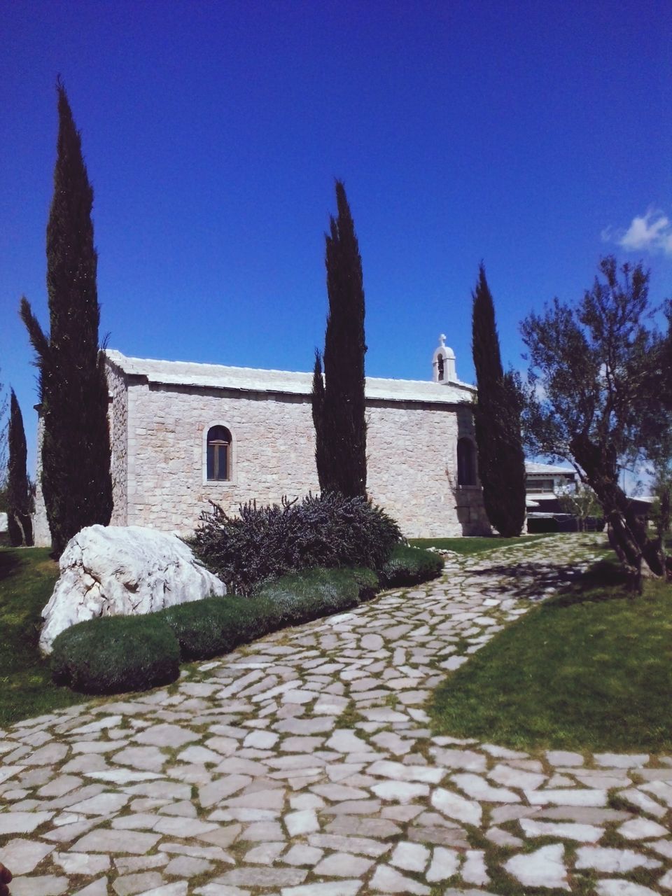 built structure, building exterior, architecture, clear sky, blue, sunlight, steps, cobblestone, tree, shadow, footpath, stone wall, stone material, sky, day, outdoors, sunny, place of worship, religion, the way forward