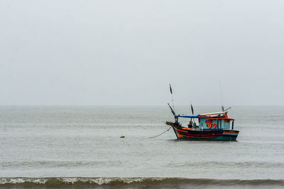 Fishing boat on sea against clear sky
