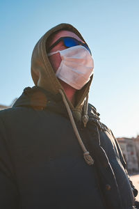 Low angle portrait of man against sky during winter