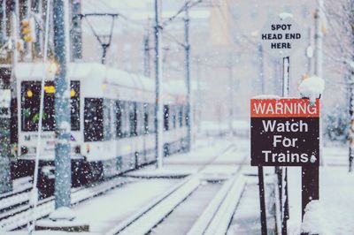 Warning sign by railroad tracks during snowfall