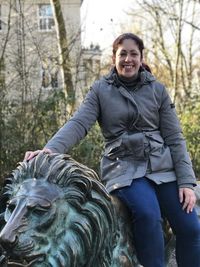 Portrait of smiling woman sitting on sculpture