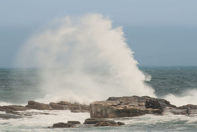 Waves splashing on shore against sky