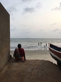 Rear view of woman looking at view of sea at shore of beach against sky