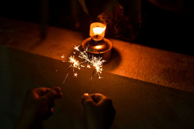 Midsection of person holding burning candle