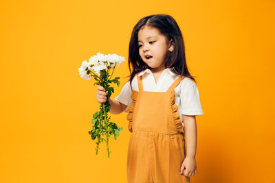 Young woman standing against yellow background