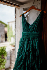 Green dress hanging on window at home