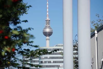 Communications tower in city against sky