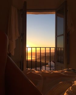 View of sea through window at sunset