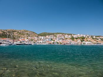 Scenic view of sea by townscape against clear blue sky