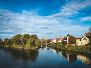 Scenic view of river by buildings against sky