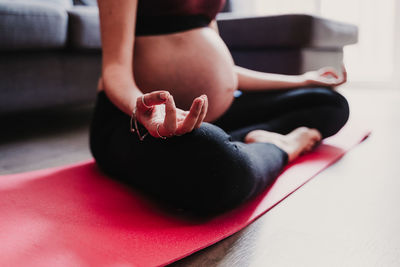 Low section of pregnant woman exercising while sitting at home