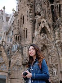 Portrait of smiling woman standing against historic building