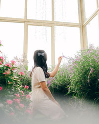 Rear view of young woman standing against plants