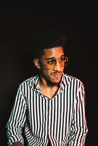 Young man standing against black background