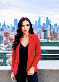 Portrait of young woman standing against buildings