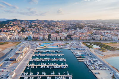 Aerial view of boats moored at harbor against cityscape