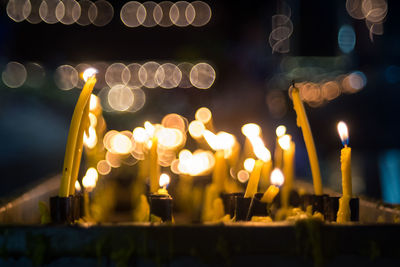 Close-up of lit candles in temple at night