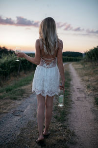 Rear view of woman standing on street during sunset