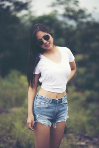 Portrait of young woman wearing sunglasses while standing on land