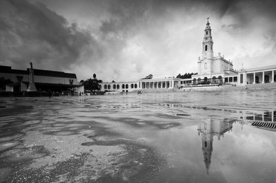 Reflection of church in puddle against sky