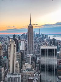 Modern buildings in city against sky during sunset