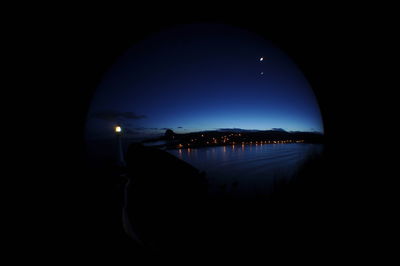 Reflection of silhouette buildings in water at night