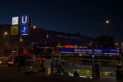 Cars on illuminated city against sky at night