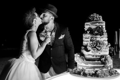 Romantic newlywed couple kissing by cake