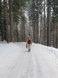 Man walking on snow covered road in forest, winter, one person.