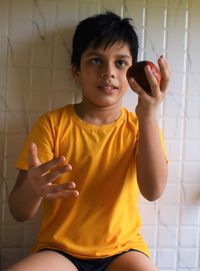 Portrait of boy holding pomegranate at home