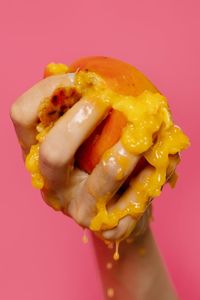 Close-up of hand holding ice cream over red background