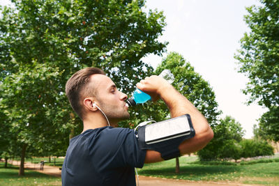 Man drinking sports drink after training. he is in an outdoor park. person