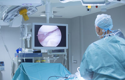 Rear view of surgeon looking at screen in operating room