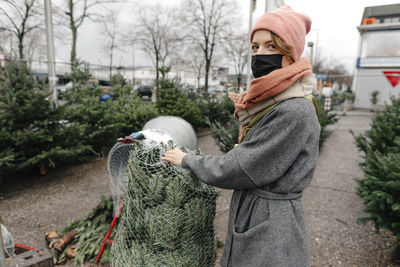 Woman buying christmas tree from market during covid-19