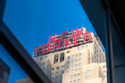 Low angle view of illuminated text on building against blue sky