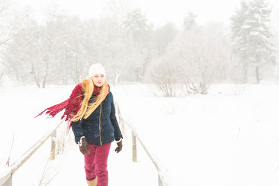 Portrait of young woman standing on snow covered trees