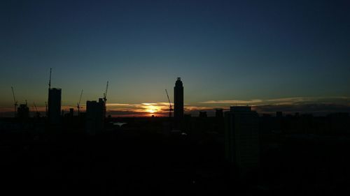 Silhouette of cityscape against sky at sunset