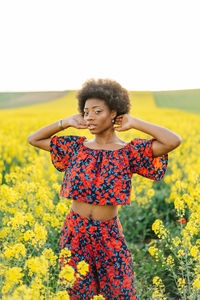 Young woman standing on yellow flower in field