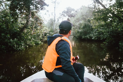 Man sitting by lake in forest