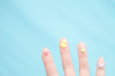 Cropped hand with patterned food against blue background