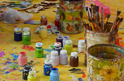 Close-up of paint bottles and brushes on table