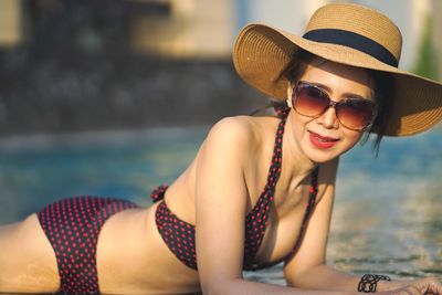 Portrait of woman in bikini wearing hat at swimming pool