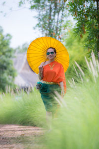 Woman with umbrella standing on grass