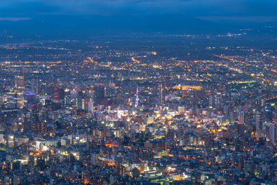 High angle view of illuminated city buildings against sky at night