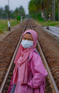 Portrait of woman standing on railroad track